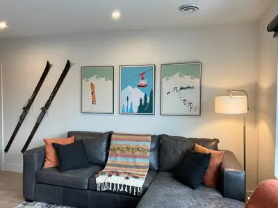 a living room with a couch and pictures on the wall at Base Camp Revy! in Revelstoke