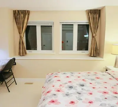a bedroom with two windows and a bed with a floral bedspread at 安静社区主楼层豪华主卧套房&独立浴室浴缸 in Coquitlam