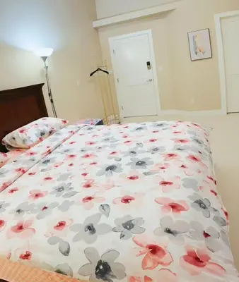 a bed with a floral comforter on it at 安静社区主楼层豪华主卧套房&独立浴室浴缸 in Coquitlam