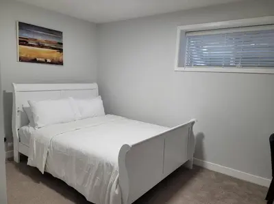 a white bed in a white bedroom with a window at Beautiful Comfy Guest Suite in West EDM in Edmonton