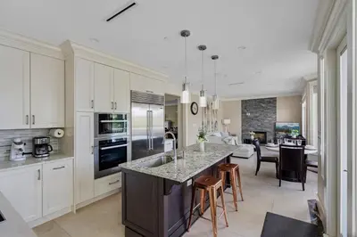 a kitchen with white cabinets and a kitchen island with chairs at Luxurious Multi-Family Home in Vancouver West, 10 Mins Downtown in Vancouver