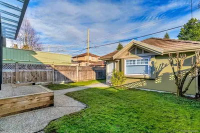 a yellow house with a fence and a yard at Cozy 1bedroom Suite in Vancouver Westside in Vancouver