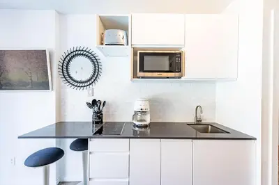 a white kitchen with a sink and a microwave at Cascade Lodge Premium Suite, with Pool & Hot Tub in Whistler