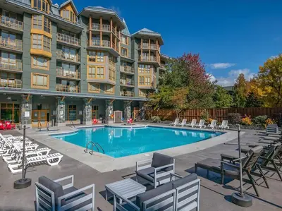 a large apartment building with a swimming pool and chairs at Cascade Lodge Premium Suite, with Pool & Hot Tub in Whistler
