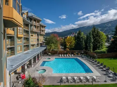 an outdoor swimming pool with chairs and a building at Cascade Lodge Premium Suite, with Pool & Hot Tub in Whistler