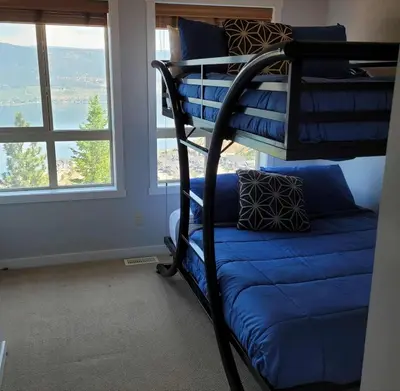 a bunk bed with a blue couch in a room with a window at La Casa Lakeside Resort - Amazing Panoramic View Lakeside House with Pools, Hot Tubs & More! in Kelowna
