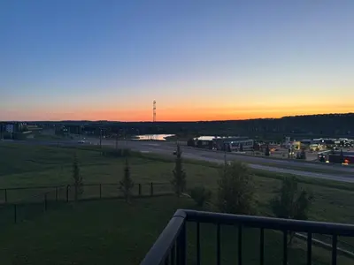 a view of a highway at sunset from a balcony at LUXURY LAKEVIEW HOME - 2500sqft of private space with 5 Beds, 4 Bath, 2 Living Rooms, Kitchen, AC, Jacuzzi, 10 Guests Max, Basement Not Included, 18-min to Airport, 20-min to Downtown, 80-min to Banff in Calgary