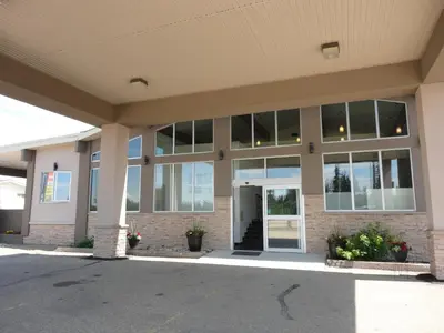 a large building with large windows and flowers in a parking lot at South Hill Motor Inn in Red Deer
