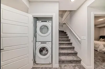 a laundry room with a washer and a staircase at Cozy Basement Suite in Calgary