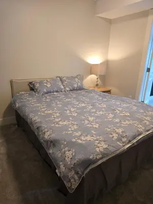 a bedroom with a bed with a blue comforter at Private 1 bedroom in Brookswood in Langley