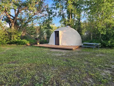 a white tent in a field with a bench at D4 Badlands Bunker Dome- 1 Queen Pet Friendly in Drumheller