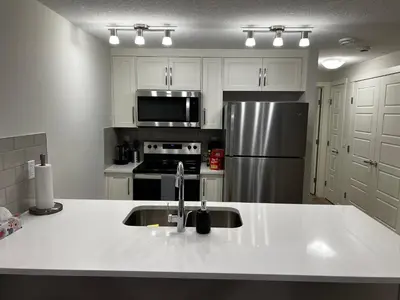 a kitchen with a sink and a stainless steel refrigerator at The Haven - cozy 1 bedroom suite in Seton SE Calgary in Calgary