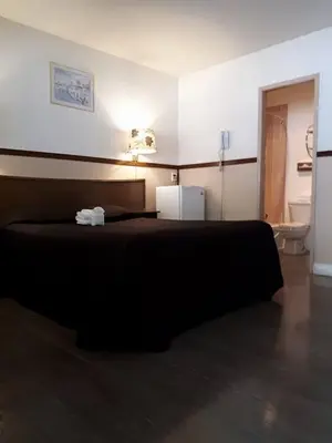 a bedroom with a black bed and a bathroom at Falcon Nest Motel in Duncan