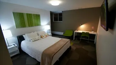 a bedroom with a bed and a desk with a green painting at HI Calgary City Centre - Hostel in Calgary
