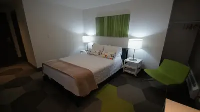 a small bedroom with a bed and a green window at HI Calgary City Centre - Hostel in Calgary