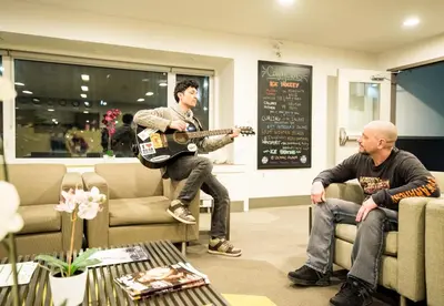 a man playing a guitar in a waiting room at HI Calgary City Centre - Hostel in Calgary
