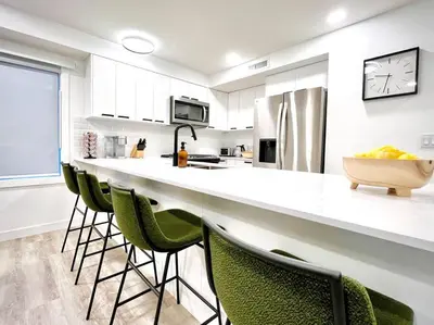 a kitchen with a large counter with green chairs at T201 Brand NEW Downtown Canmore 3BD & 2BT, BBQ, Free Parking in Canmore