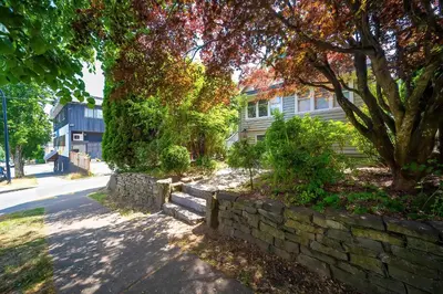 a stone retaining wall in front of a house at Charming Home Near UBC with Parking & Backyard in Vancouver