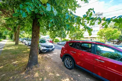 a red car parked next to a tree at Charming Home Near UBC with Parking & Backyard in Vancouver