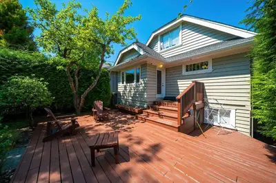 a deck with two chairs and a house at Charming Home Near UBC with Parking & Backyard in Vancouver