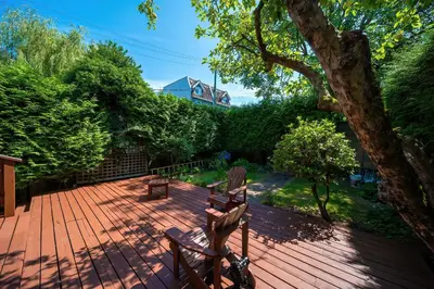a wooden deck with two chairs and a tree at Charming Home Near UBC with Parking & Backyard in Vancouver