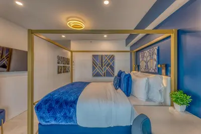 a bedroom with a large bed with blue sheets at Art Deco Broadway Queen Room in Vancouver