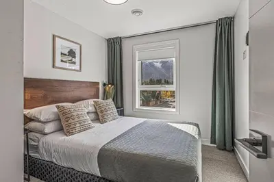a bedroom with a large bed and a window at K202 Hot tub, Pool, MTN view, AC, free parking in Canmore