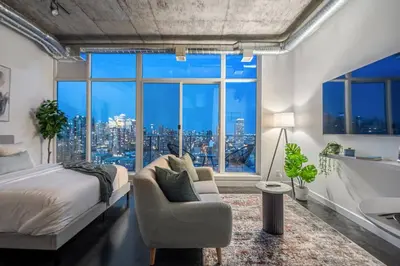a bedroom with a bed and a large window at Studio Just Steps from Stampede Park, Luxury Living in Calgary