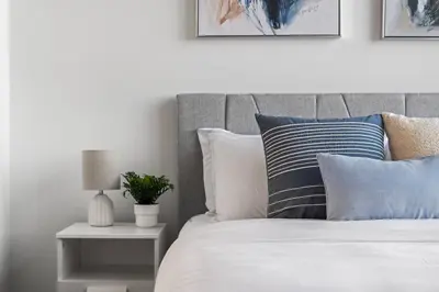 a bedroom with a bed with pillows and a table at Studio Just Steps from Stampede Park, Luxury Living in Calgary
