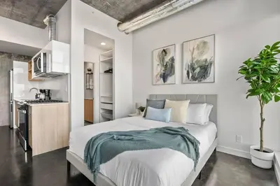 a bedroom with a large bed and a kitchen at Studio Just Steps from Stampede Park, Luxury Living in Calgary