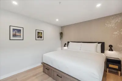 a bedroom with a large bed with white sheets at The Oak Hotel in Nelson