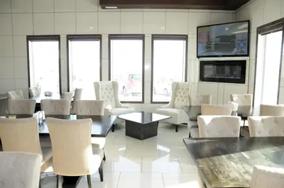 a dining room with tables and chairs and a flat screen tv at High Point Inn & Suites Peace River in Peace River