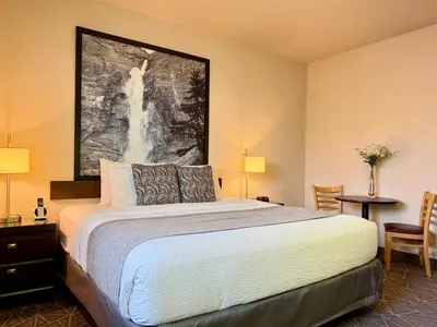 a bedroom with a bed and a painting on the wall at High Point Inn & Suites Peace River in Peace River