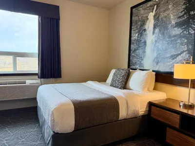 a hotel room with a bed and a window at High Point Inn & Suites Peace River in Peace River