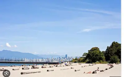 a beach with a bunch of people laying on the sand at Boutique Beach Apartment in Vancouver