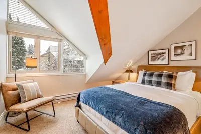 a bedroom with a bed and a chair and a window at The Crest, Spacious, Central Condo, Free Parking in Whistler