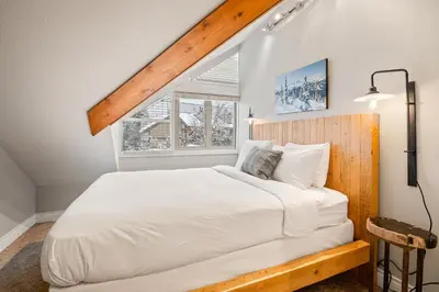 a bedroom with a large white bed with a wooden headboard at The Nest, Central, Luxury Unit, Free Parking in Whistler