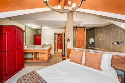 a bedroom with a red bed and a bathroom at The Den, Heart of Village, Free Parking in Whistler