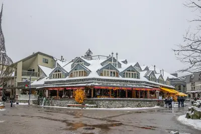a building with a snow covered roof on a street at The Den, Heart of Village, Free Parking in Whistler