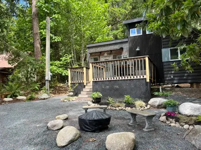 a house with a deck and a bench in front of it at Malaspina Strait Tiny Home in Powell River