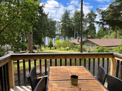 a wooden table on a deck with chairs at Malaspina Strait Tiny Home in Powell River