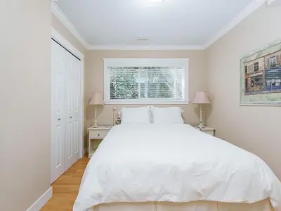 a white bedroom with a white bed and a window at Ferry Walk House in West Vancouver