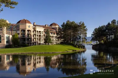 a building next to a river with its reflection in the water at The Royal Kelowna - Bellstar Hotels & Resorts in Kelowna