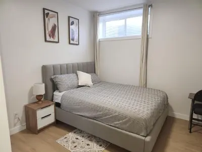 a small bedroom with a bed and a window at Brand New Deluxe 2 Bedroom Suite with AC & Den in Calgary