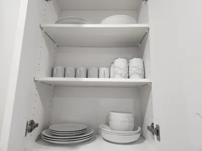 a cupboard filled with plates and bowls and dishes at Brand New Deluxe 2 Bedroom Suite with AC & Den in Calgary