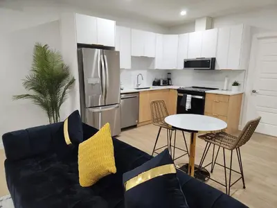 a living room with a couch and a table in a kitchen at Brand New Deluxe 2 Bedroom Suite with AC & Den in Calgary