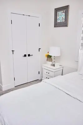 a white bedroom with a white closet and a bed at Brand-new three bedroom guest suite in the desirable neighbourhood in Prince George