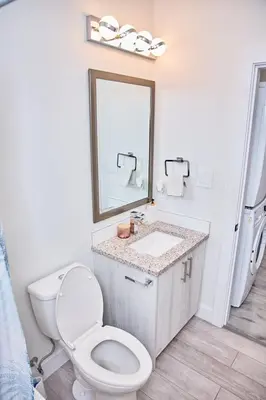 a bathroom with a toilet and a sink and a mirror at Brand-new three bedroom guest suite in the desirable neighbourhood in Prince George