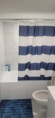 a bathroom with a blue and white shower curtain and a toilet at A Cozy home away from home at South East Calgary in Calgary