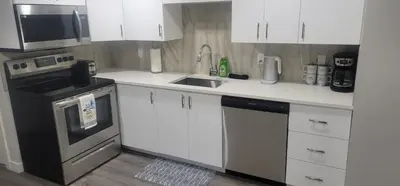 a kitchen with white cabinets and a sink and a stove at A Cozy home away from home at South East Calgary in Calgary